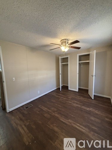 A room with a ceiling fan and wooden flooring.