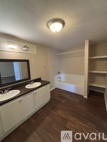 A bathroom with a brown floor and white cabinets.