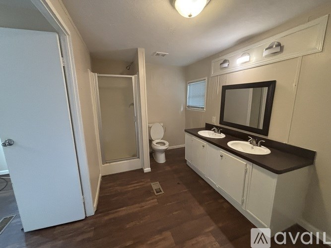 A bathroom with a toilet, sink, mirror, and a shower.