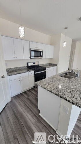 A kitchen with white cabinets and a granite countertop.