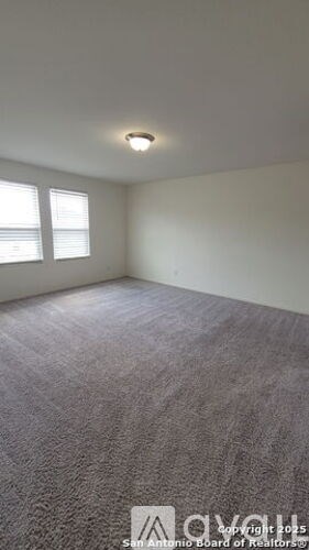A carpeted room with a window and a ceiling light.