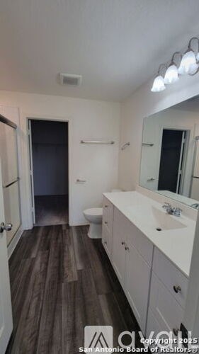 A bathroom with a toilet, sink, and mirror.