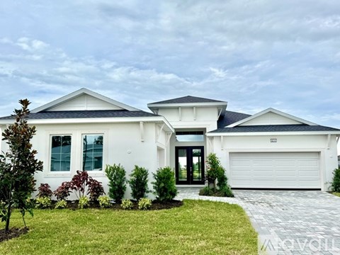 A white house with a black roof and a grey driveway.