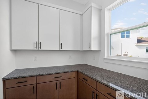 A kitchen with white cabinets and a granite countertop.