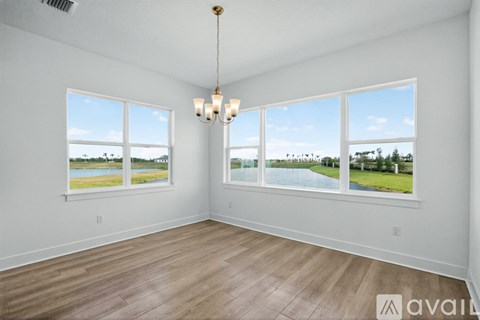 A room with a chandelier and large windows overlooking a body of water.