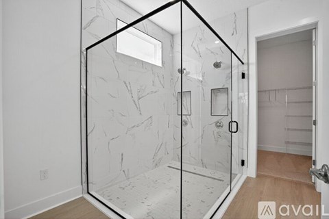 A bathroom with a marble patterned shower enclosure.