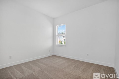 A room with a window showing a view of a building and trees outside.