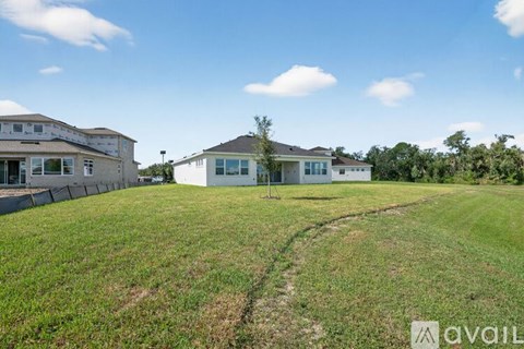 A grassy field with a house and a fence in the background.