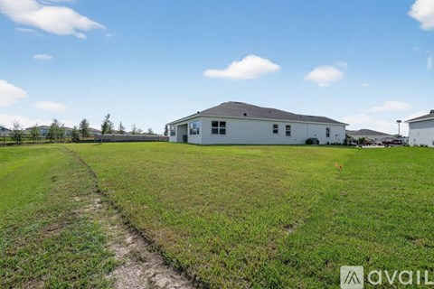 A house is situated in a grassy field with a clear blue sky above.