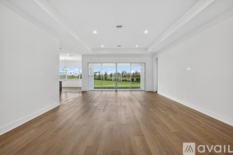 A spacious room with wooden flooring and white walls.