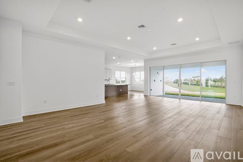 A spacious room with wooden flooring and white walls.