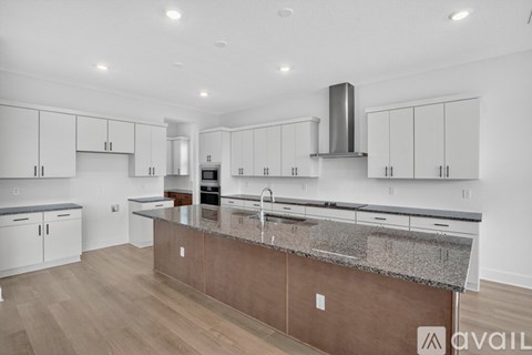 A modern kitchen with a central island and wooden flooring.