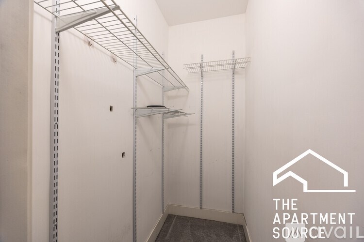 A white wall with a metal shelf and a logo that says "The Apartment Source".