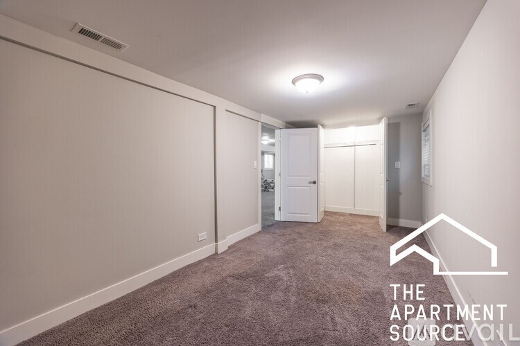 A spacious, empty apartment with a carpeted floor and white walls.