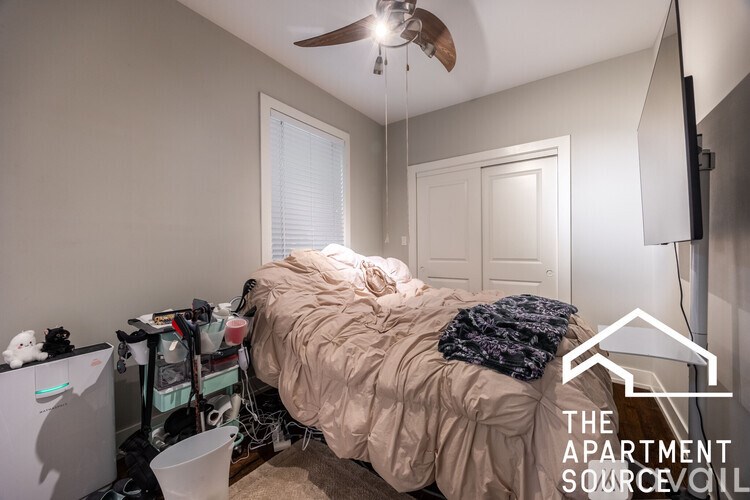 A messy bedroom with a bed covered in a blanket and pillows.
