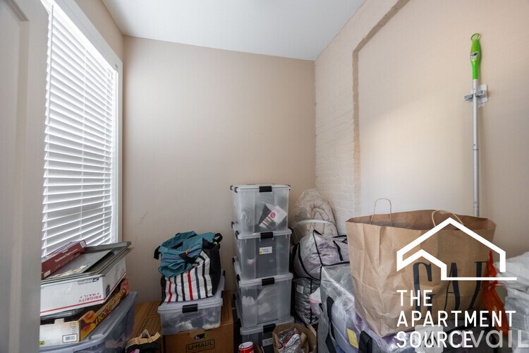 A room with a lot of clutter and a sign that says "The Apartment Source".