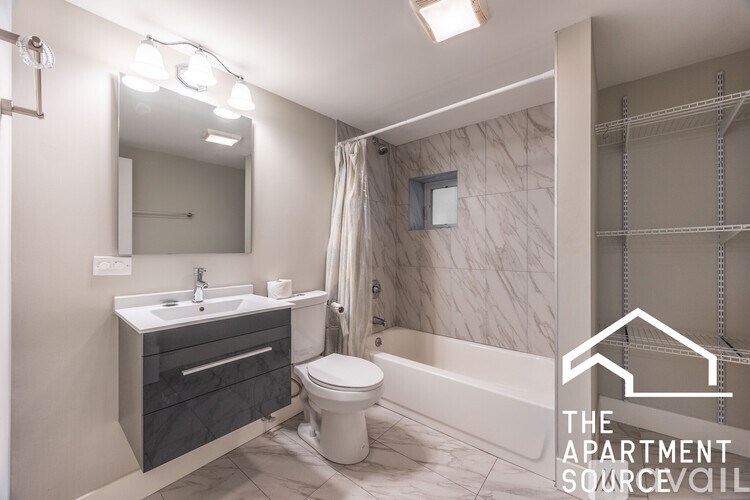 A modern bathroom with a sink, toilet, and a large mirror.
