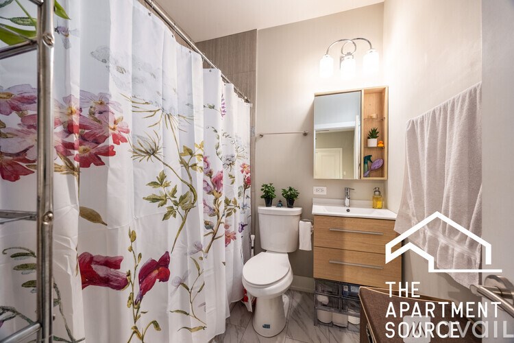 A bathroom with a floral shower curtain and a white toilet.