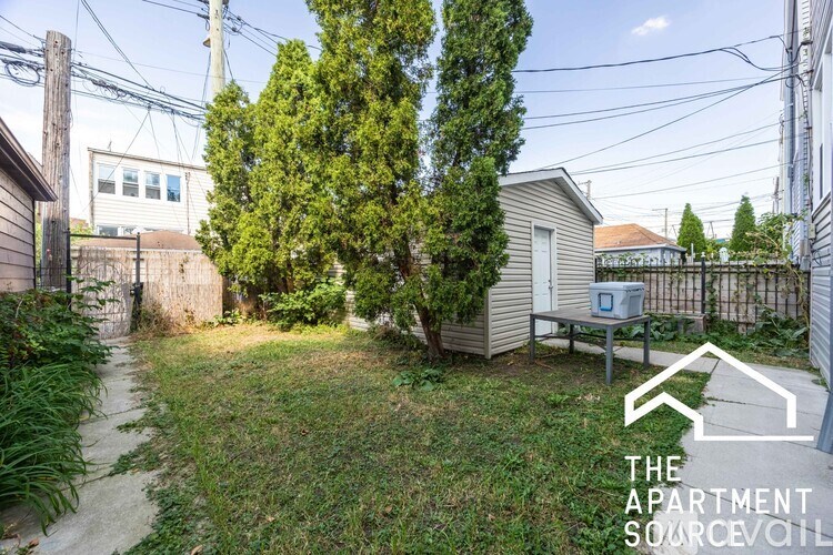 A backyard with a tree, a bench, and a shed.