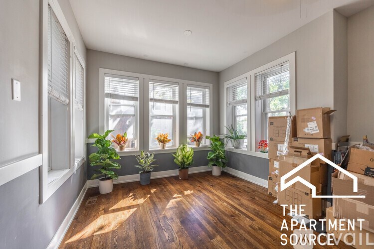 A room with wooden floors and a window with a plant in it.