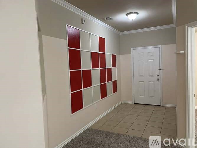 A room with a white door and a wall with red and white squares.