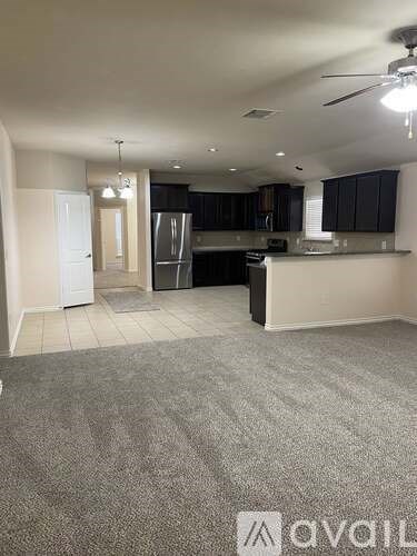 A spacious kitchen with a refrigerator, sink, and cabinets.