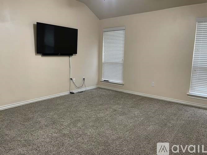 A room with a flat screen TV mounted on the wall and a carpeted floor.