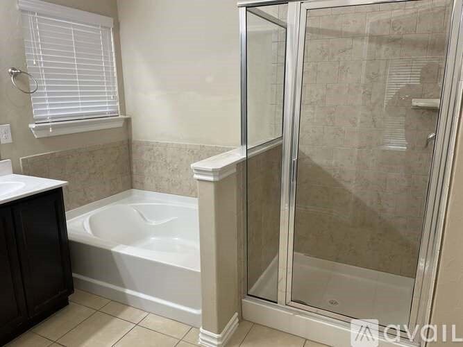 A white bathtub in a bathroom with a glass shower door.