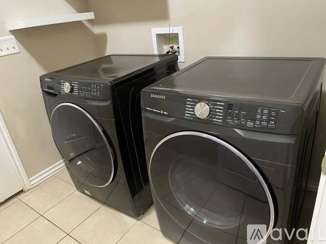 Two black front loading washing machines in a laundry room.