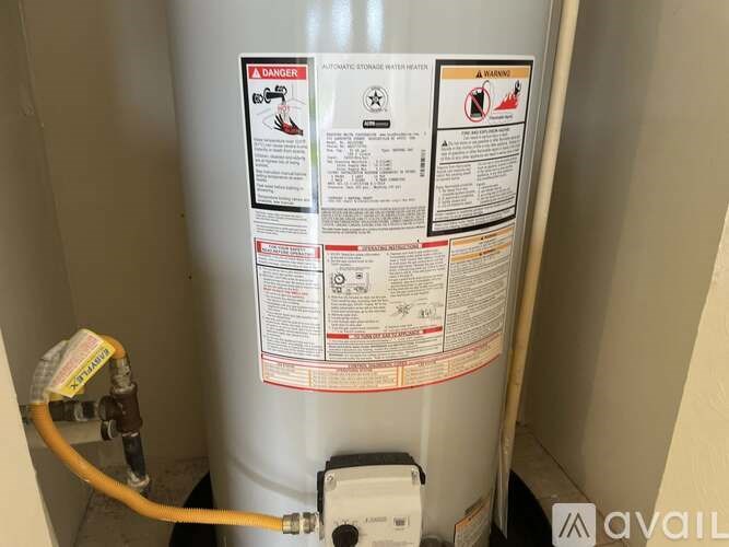 A water heater with a yellow hose connected to it.