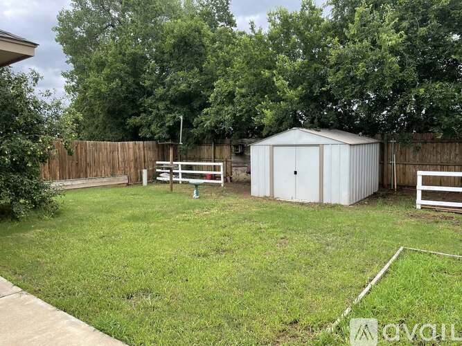 A backyard with a shed, fence, and trees.