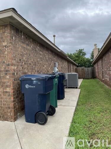 A blue and green dumpster is parked on a concrete driveway.