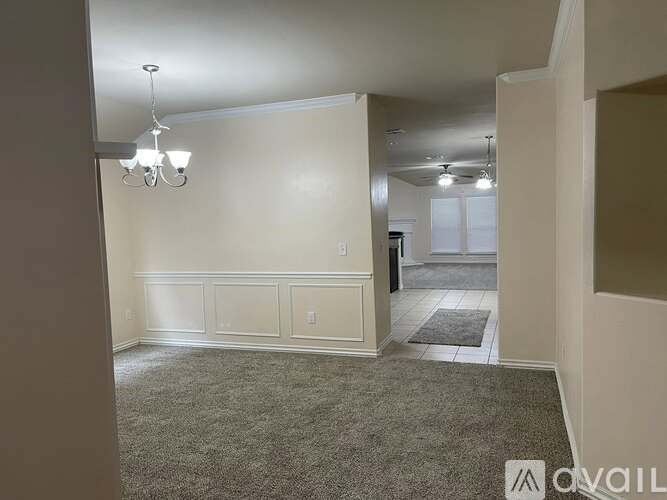 A room with a carpeted floor and a chandelier hanging from the ceiling.