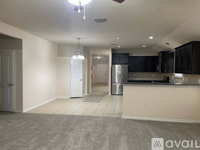 A spacious living area with a kitchen in the background.
