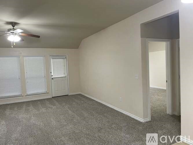 A room with a ceiling fan and carpeted floor.