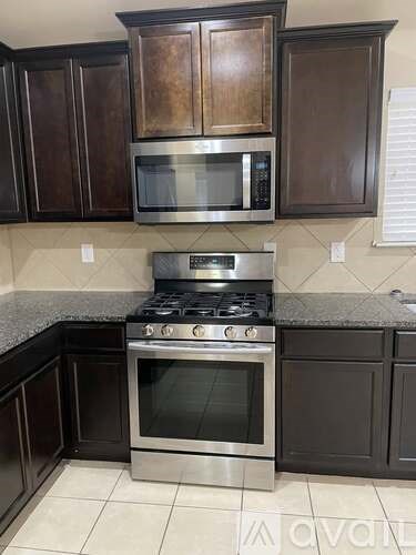 A kitchen with dark brown cabinets and a stainless steel oven.