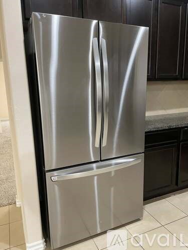 A stainless steel refrigerator with a water dispenser on the door.
