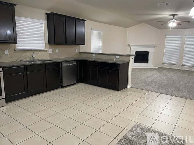 A kitchen with black cabinets and a white fireplace.