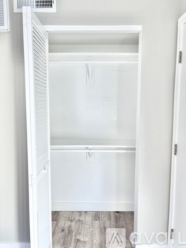 A white closet with a shelf and a door.