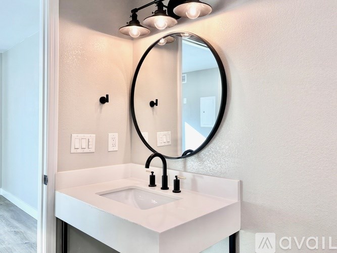 A bathroom sink with a round mirror above it.