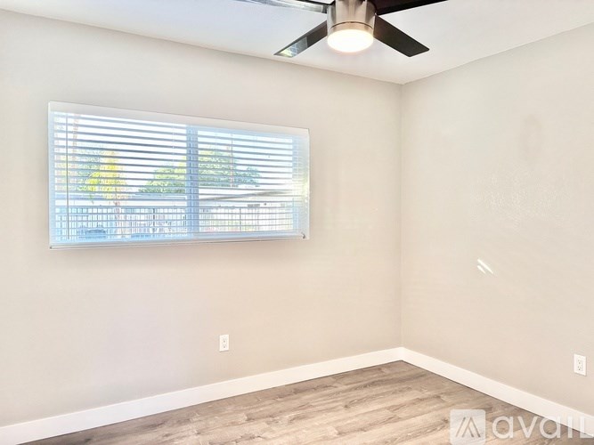 A room with a ceiling fan and a window with blinds.