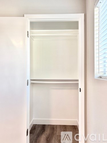 A white closet with a shelf and a window.