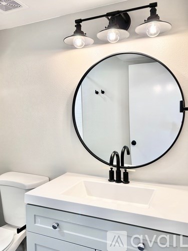 A bathroom with a white sink and a round mirror.