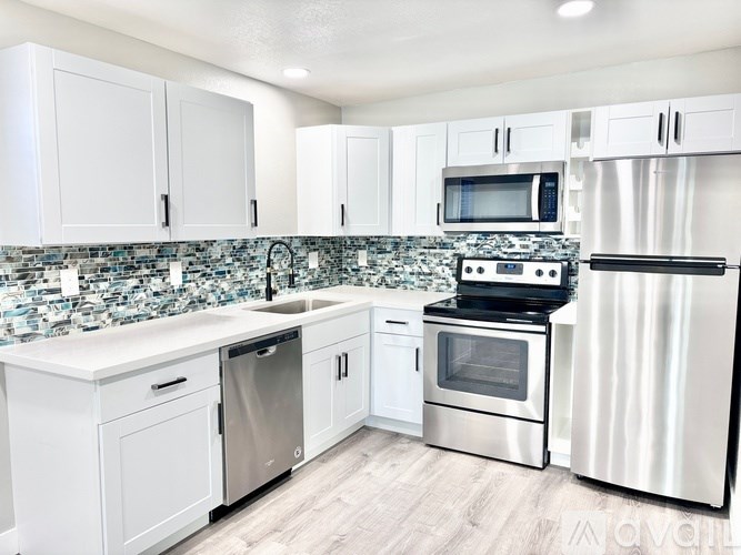 A kitchen with white cabinets and a tiled backsplash.