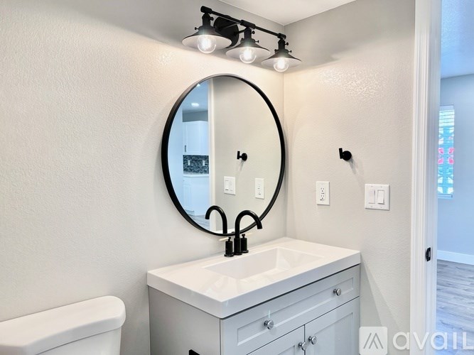 A bathroom with a white sink and a round mirror.