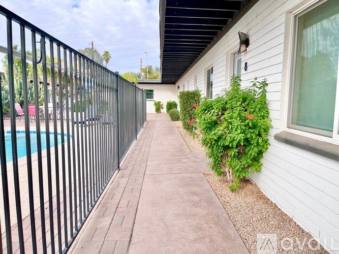 A black metal fence borders a pool and a concrete walkway.