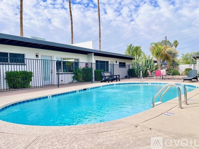 A swimming pool in front of a house with a fence around it.
