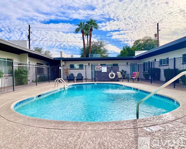 A pool surrounded by a black fence with a cloudy sky in the background.