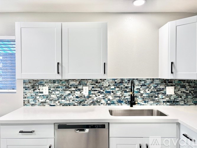 A modern kitchen with white cabinets and a tiled backsplash.