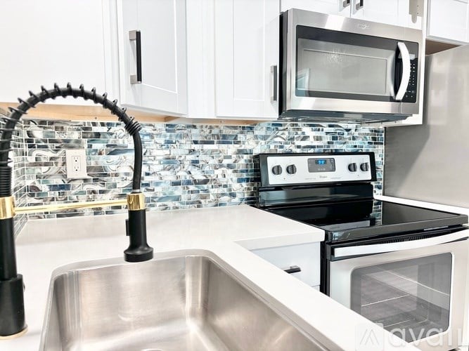 A kitchen with a stainless steel sink and a black faucet.